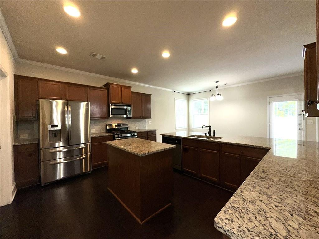 1365 Delo Lane Cumming, GA 30041 - Photo 8 of 43 a kitchen with stainless steel appliances kitchen island granite countertop a refrigerator a sink dishwasher and a stove with wooden floor
