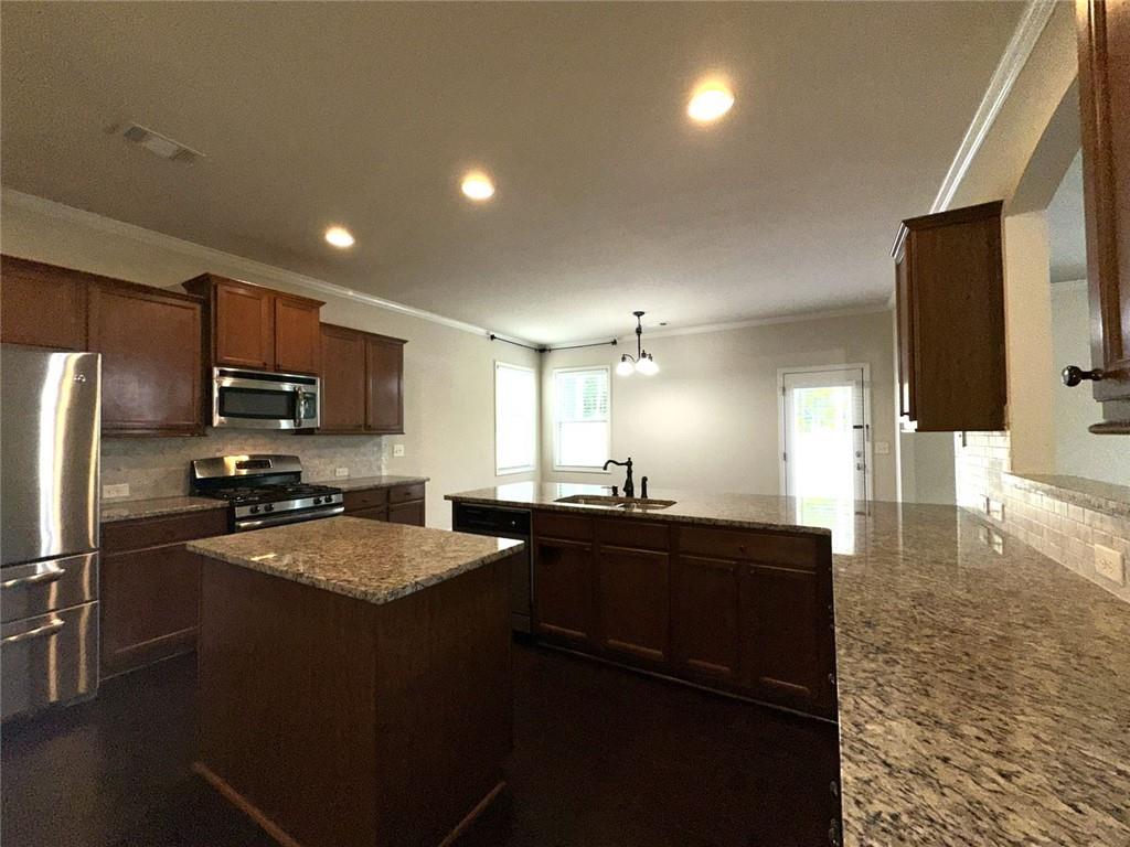 1365 Delo Lane Cumming, GA 30041 - Photo 9 of 43 a kitchen with granite countertop a refrigerator a sink a stove a dining table and chairs