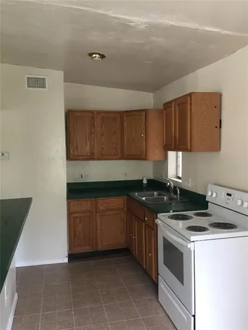 a kitchen with granite countertop a stove top oven sink and cabinets