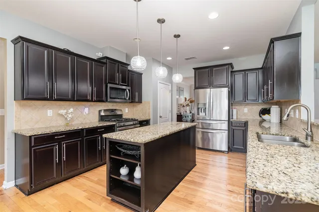 a kitchen with stainless steel appliances granite countertop a sink stove and refrigerator