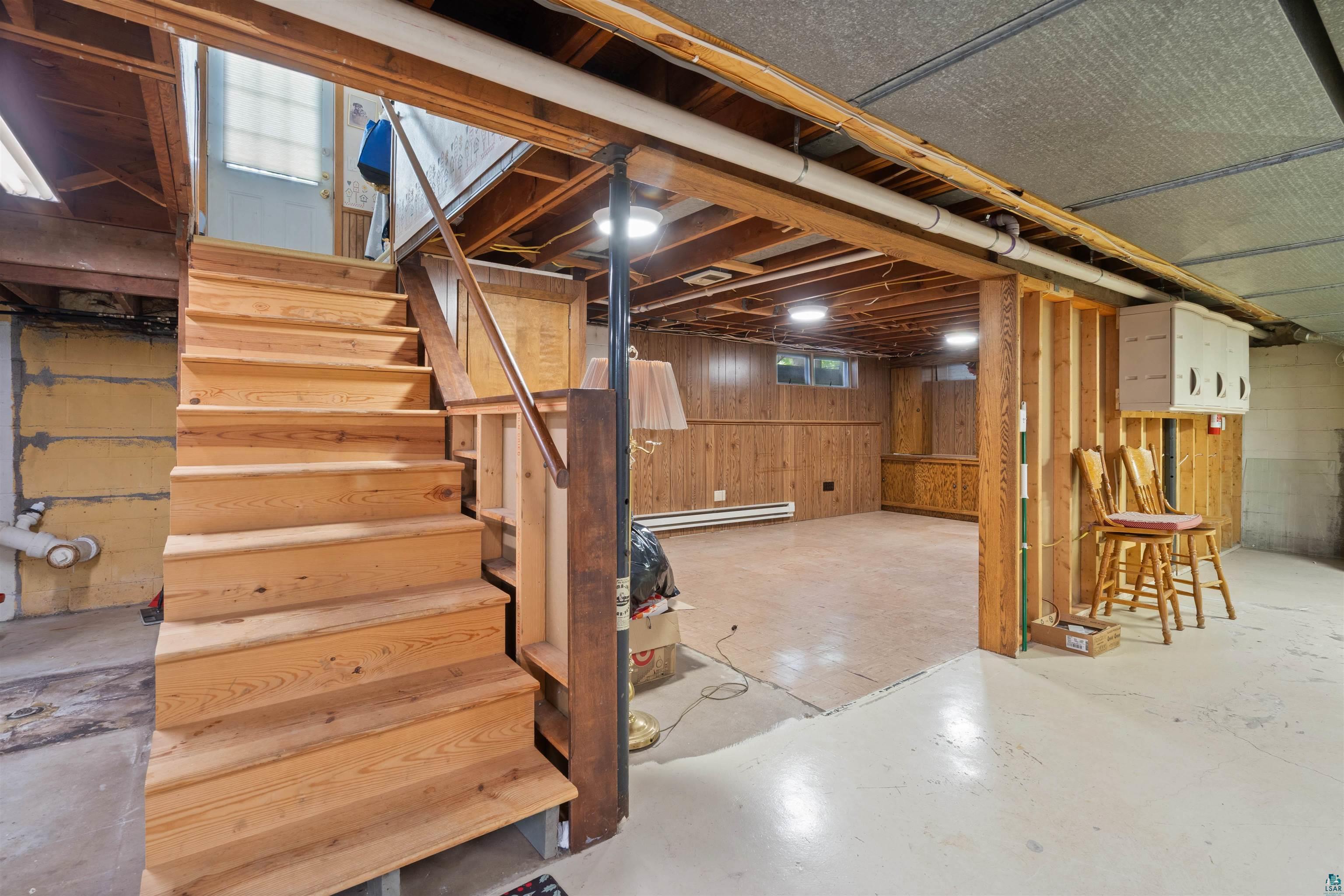 3711 Getchell Road Hermantown, MN 55811 - Photo 18 of 31 Wooden staircase leading to a lower level featuring wood paneling, exposed ceiling joists, and concrete flooring