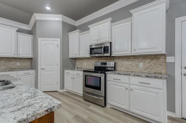 a kitchen with granite countertop white cabinets and white appliances