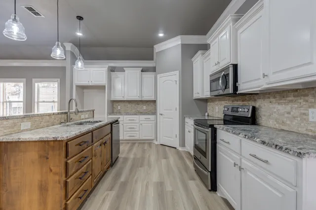 a kitchen with granite countertop a sink a counter top space stainless steel appliances and cabinets