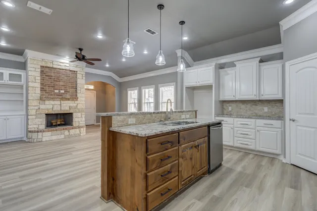 a kitchen with kitchen island granite countertop a stove and a wooden floors
