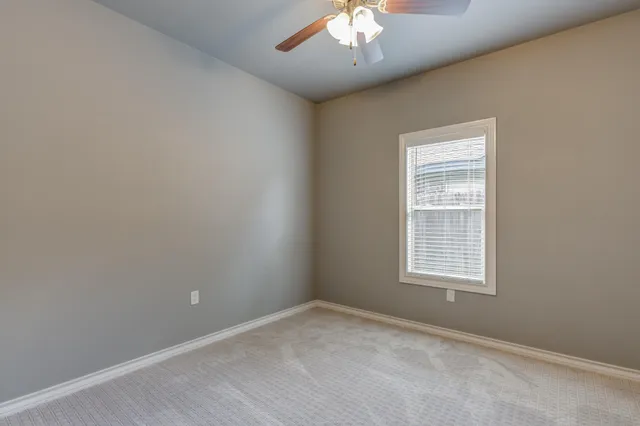 an empty room with a chandelier fan and window