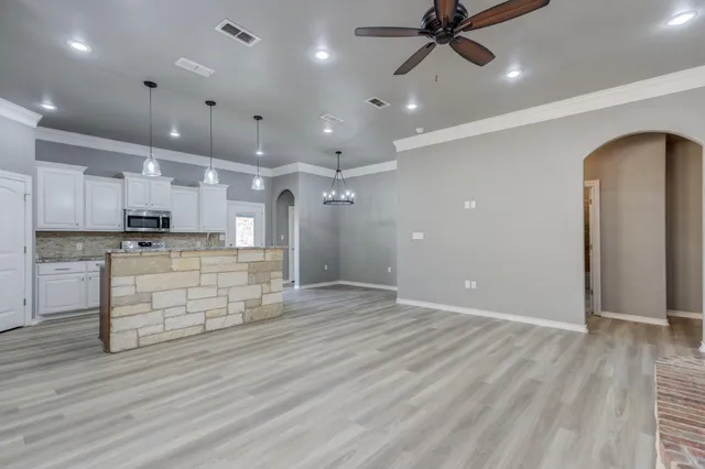 an open kitchen with kitchen island white cabinetry and wooden floor