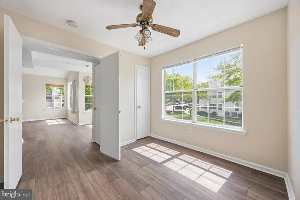 a view of an empty room with a window and wooden floor