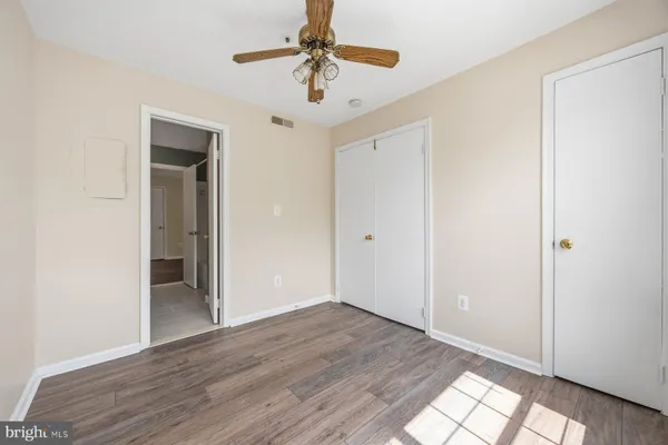 an empty room with wooden floor chandelier fan and closet area