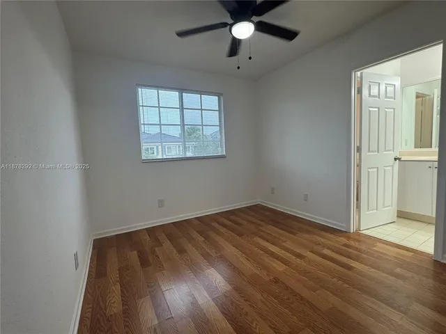 an empty room with wooden floor chandelier fan and windows