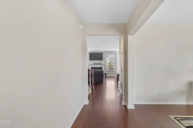 a view of a hallway with wooden floor and a bathroom