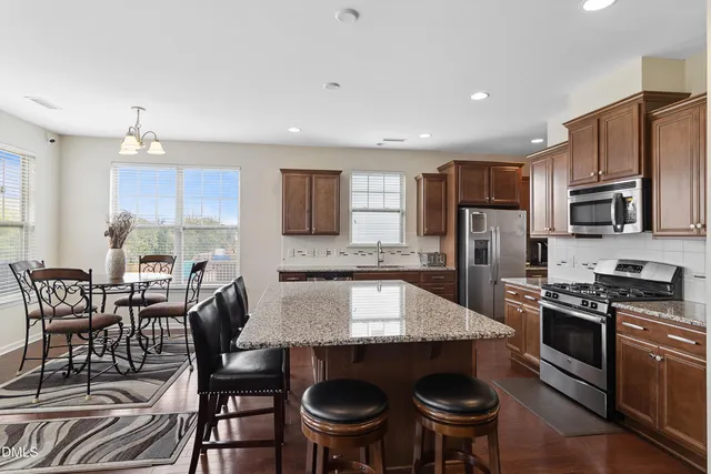 a kitchen with stainless steel appliances a dining table and chairs