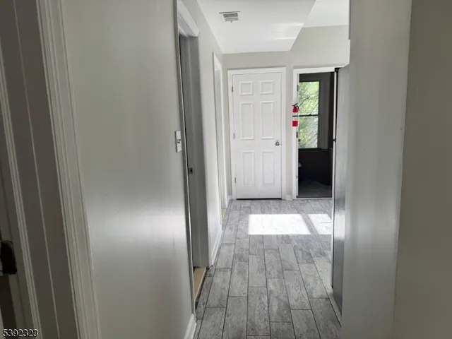 a view of a hallway with wooden floor and closet