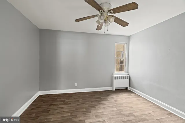 an empty room with wooden floor fan and windows