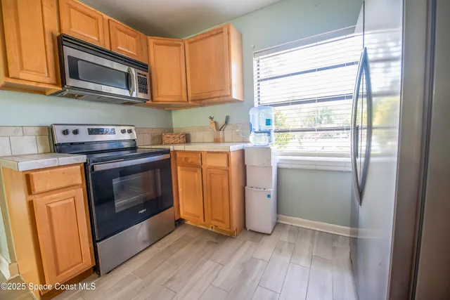 a kitchen with granite countertop wooden cabinets stainless steel appliances and a window