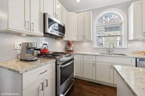 a kitchen with granite countertop a sink stainless steel appliances and white cabinets