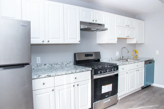 a kitchen with stainless steel appliances granite countertop white cabinets and a stove a oven with white countertops