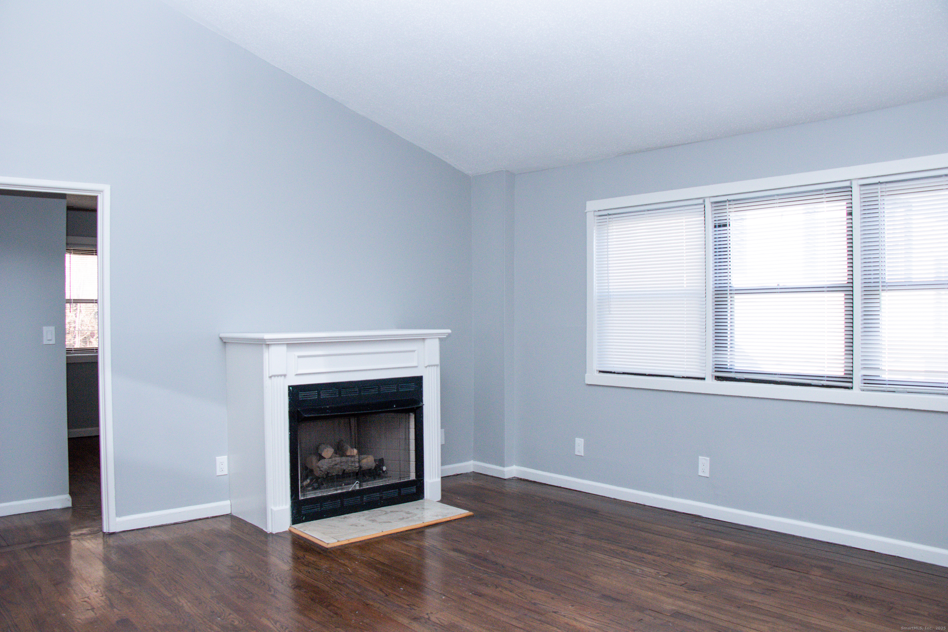 98 Kaye Vue Drive Hamden, CT 06514 - Photo 3 of 7 an empty room with wooden floor windows and fireplace