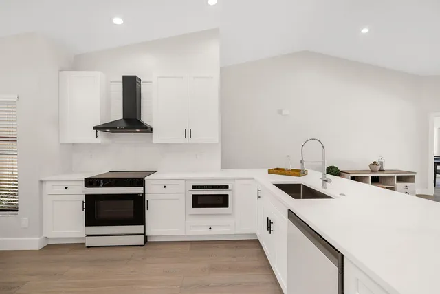 a kitchen with a sink a stove and white cabinets