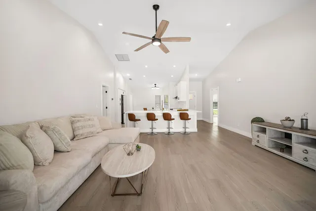 a living room with furniture kitchen view and a chandelier