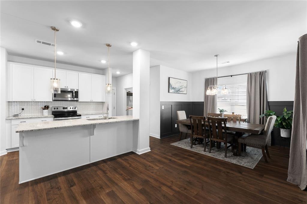2253 Cotton Gin Row Jefferson, GA 30549 - Photo 12 of 45 a kitchen with stainless steel appliances granite countertop a dining table chairs stove a refrigerator and cabinets
