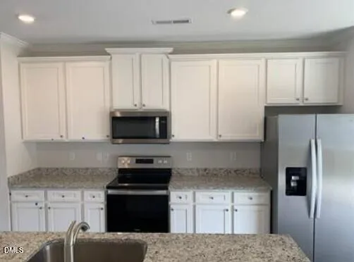 a kitchen with granite countertop white cabinets and stainless steel appliances