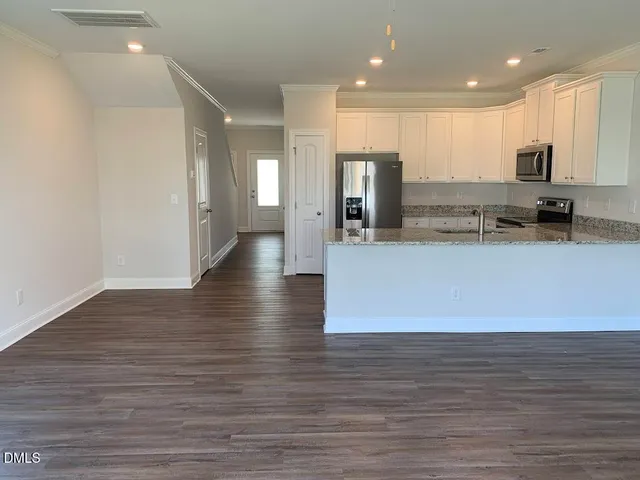 a large kitchen with stainless steel appliances a large counter top and a wooden floors