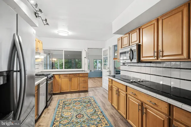 a kitchen with stainless steel appliances granite countertop a refrigerator a sink and white cabinets
