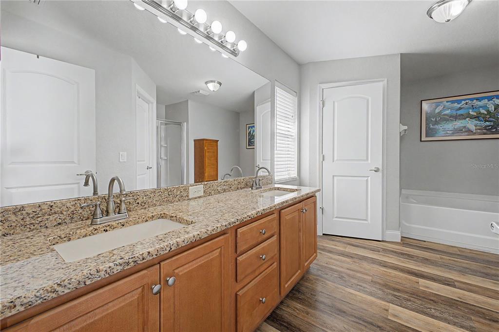 11213 Flock Avenue Weeki Wachee, FL 34613 - Photo 23 of 46 a spacious bathroom with a granite countertop double vanity sink a mirror and a bathtub