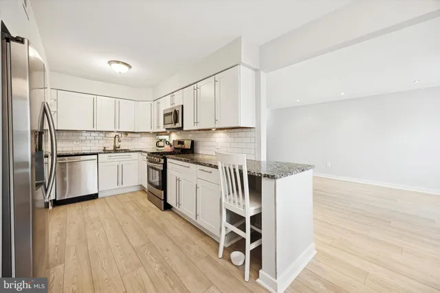 a kitchen with granite countertop white cabinets and stainless steel appliances