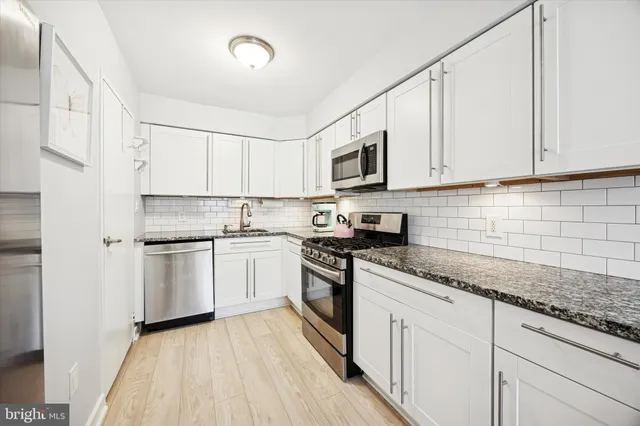 a kitchen with granite countertop white cabinets and white appliances