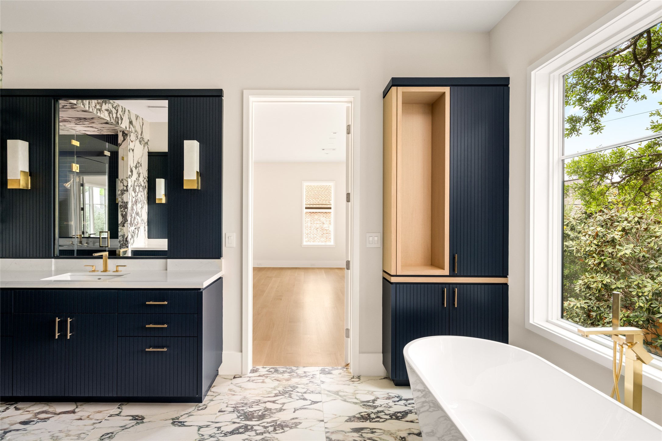 4006 Overbrook Lane Houston, TX 77027 - Photo 29 of 50 Primary bath with striking contrast, featuring fluted navy cabinetry, quartzite surfaces, and warm white oak accents.