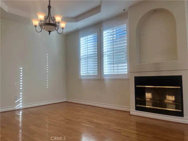 a view of an empty room with wooden floor fireplace and a window