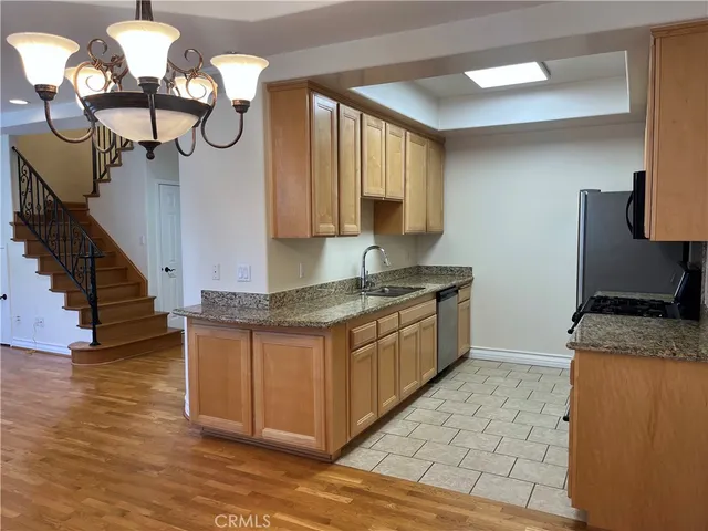 a kitchen with granite countertop a stove a sink and a wooden floors