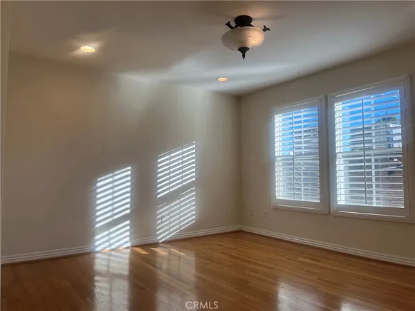 a view of empty room with wooden floor and fan