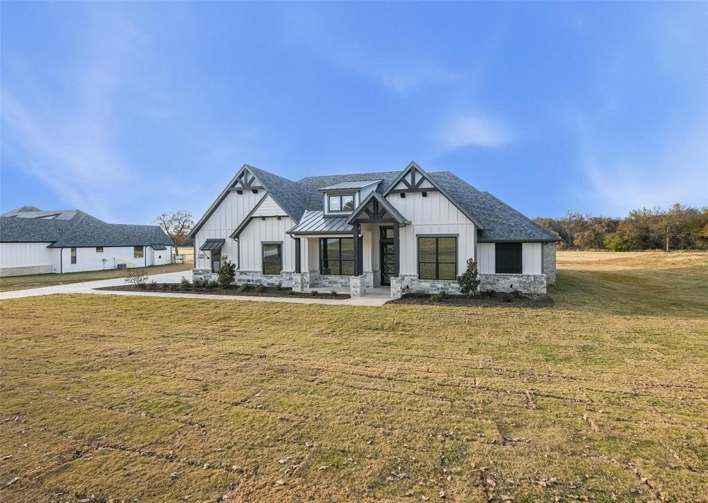 Modern farmhouse style home with a front yard, board and batten siding, a standing seam roof, and a metal roof