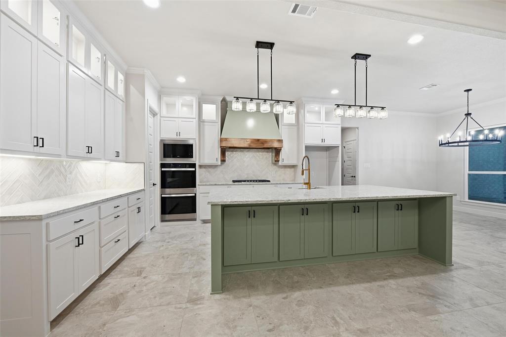 189 Rio Rancho Drive Decatur, TX 76234 - Photo 14 of 36 Kitchen featuring white cabinets, glass insert cabinets, a spacious island, decorative light fixtures, and light stone countertops