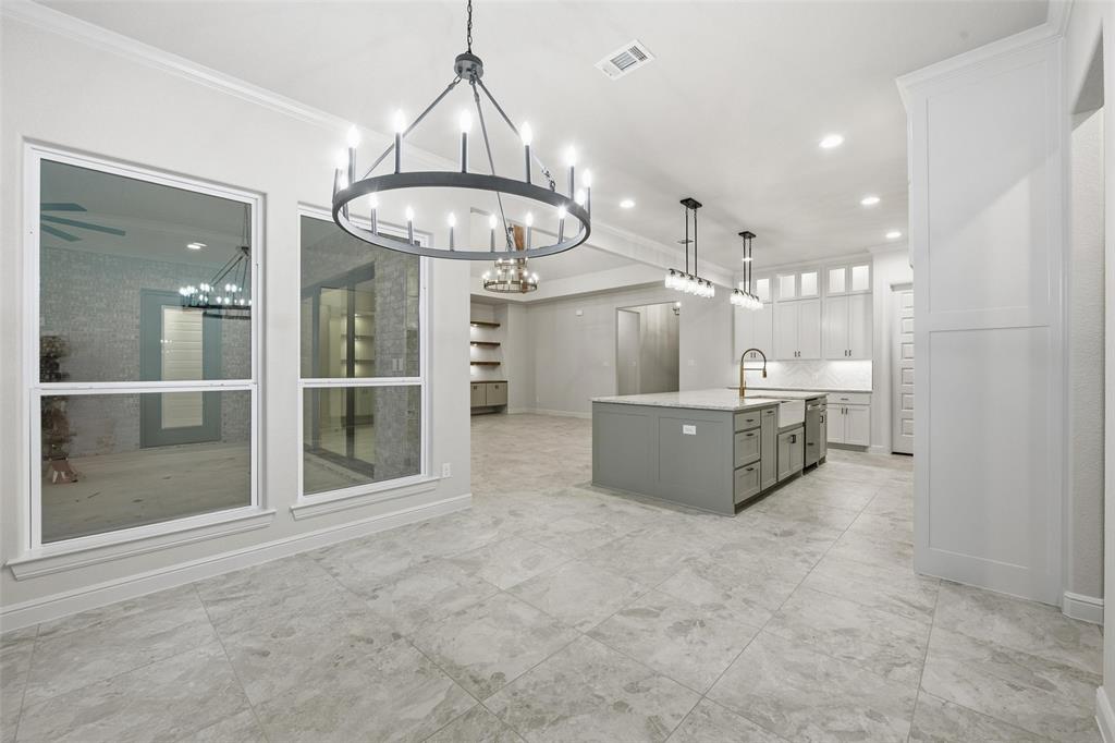 189 Rio Rancho Drive Decatur, TX 76234 - Photo 15 of 34 Kitchen with hanging light fixtures, an island with sink, white cabinets, decorative backsplash, and ornamental molding
