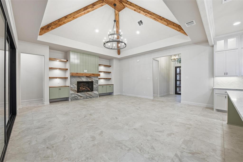 189 Rio Rancho Drive Decatur, TX 76234 - Photo 9 of 34 Unfurnished living room featuring a chandelier, a high end fireplace, built in shelves, a tray ceiling, and recessed lighting