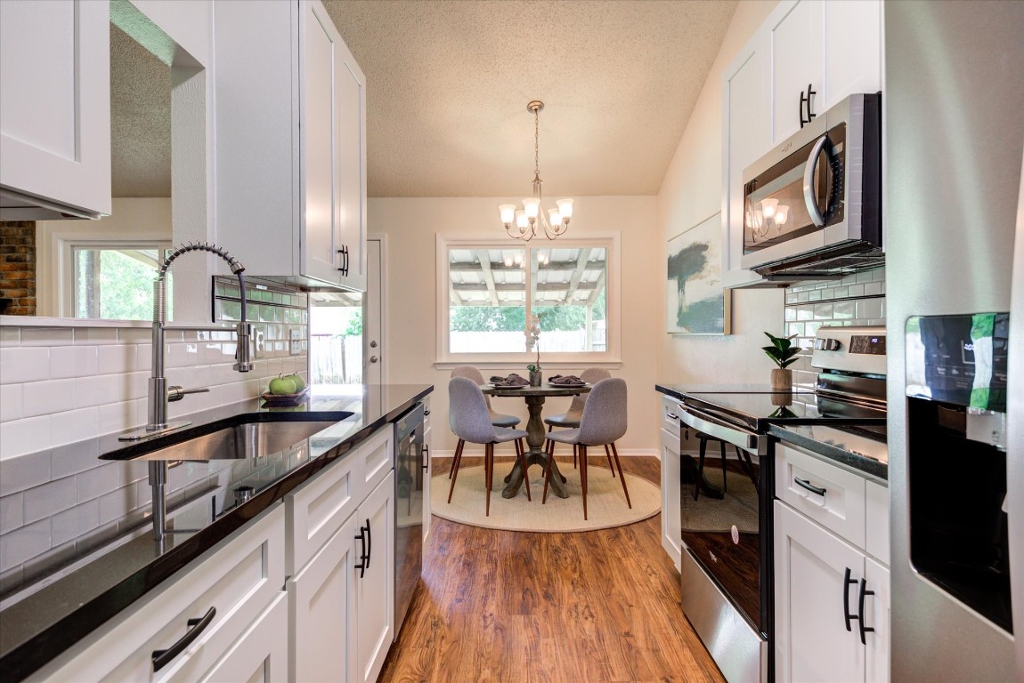 a kitchen with granite countertop a stove top oven a sink a dining table and chairs