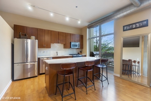 700 North Larrabee Street, Unit 115 Chicago, IL 60654 - Photo 3 of 20 a kitchen with stainless steel appliances granite countertop a refrigerator a stove a sink a dining table and chairs with wooden floor