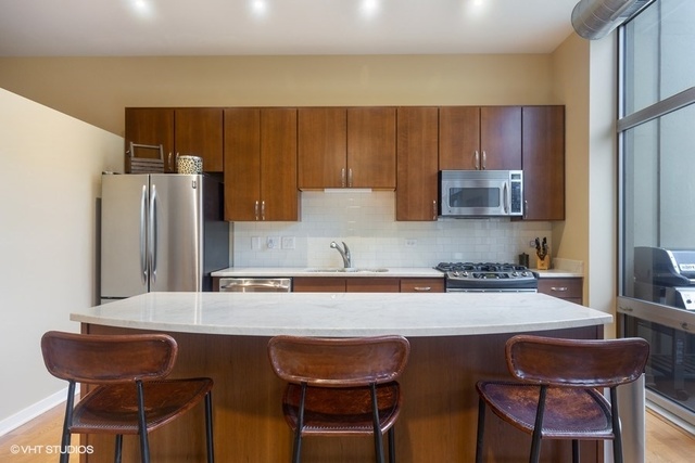 700 North Larrabee Street, Unit 115 Chicago, IL 60654 - Photo 6 of 20 a kitchen with stainless steel appliances granite countertop a table chairs refrigerator and sink