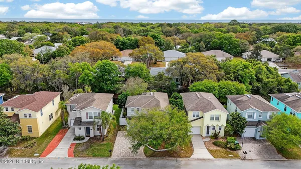 an aerial view of residential houses with outdoor space and trees