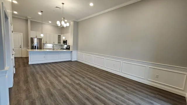a view of a kitchen with kitchen island a sink wooden floor and stainless steel appliances