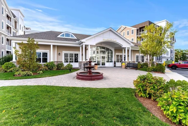 a view of a white house with a big yard and potted plants
