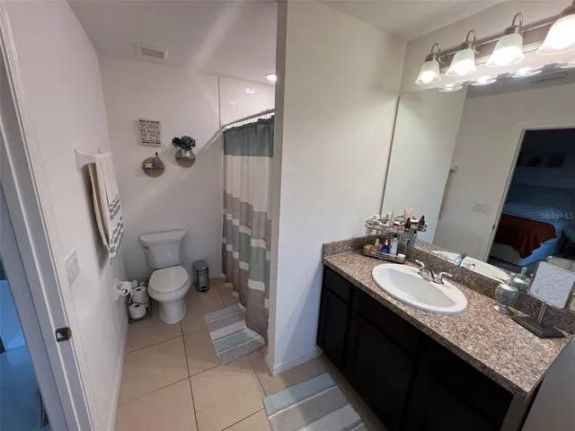 a bathroom with a granite countertop sink toilet and a mirror