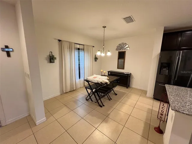 a living room with furniture a dining table and a refrigerator