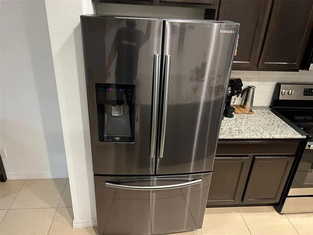 a metallic refrigerator freezer sitting in a kitchen