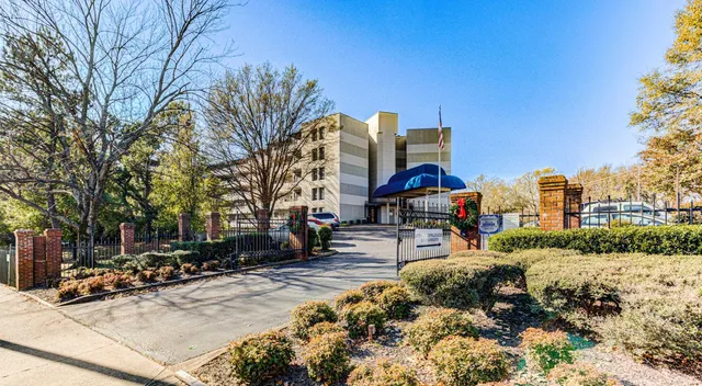 a front view of a building with lot of cars and trees