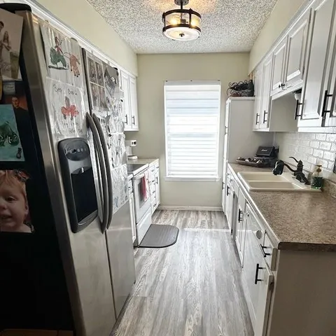 a kitchen with stainless steel appliances granite countertop a refrigerator a sink a stove and a refrigerator