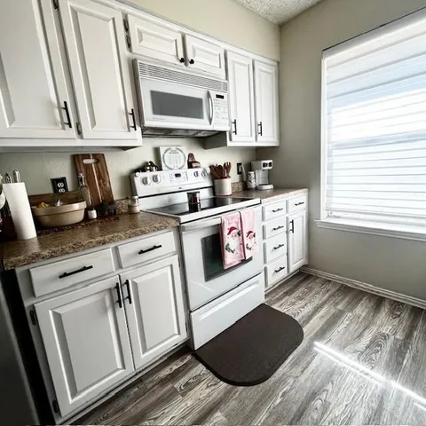 a kitchen with granite countertop cabinets stainless steel appliances a sink and a window